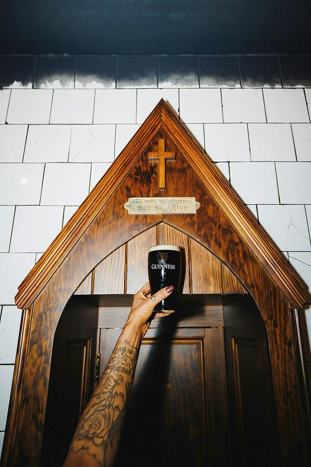 A hand holding a pint of Guinness inside Dirty O’Sullivans Irish pub in Manchester city centre