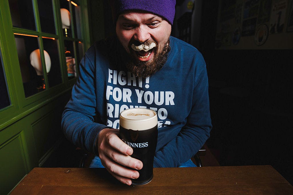 Customer enjoying a pint of Guinness inside Dirty O’Sullivans Irish pub in Manchester city centre